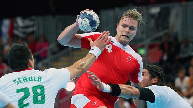 Ein Handballspieler im roten Trikot wirft den Ball während eines Spiels.