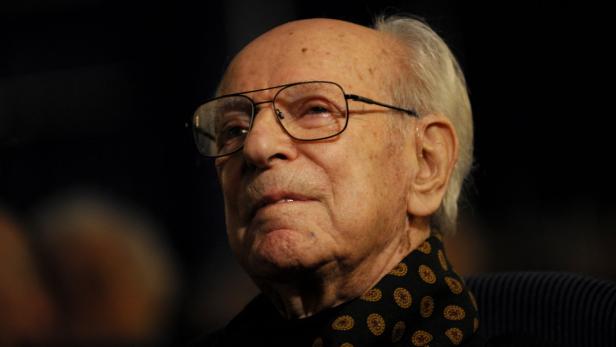 Ein älterer Mann mit Brille und gemustertem Schal blickt nach oben.