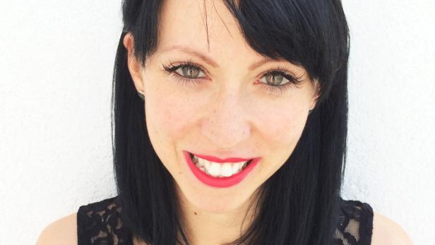 Eine Frau mit dunklen Haaren und einem Gucci-Stirnband lächelt in die Kamera.