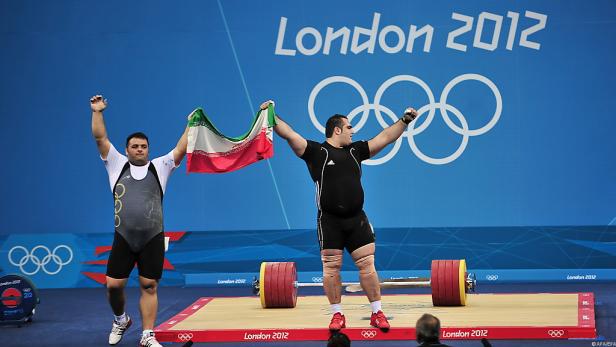 Zwei Gewichtheber feiern bei den Olympischen Spielen 2012 in London mit der iranischen Flagge.
