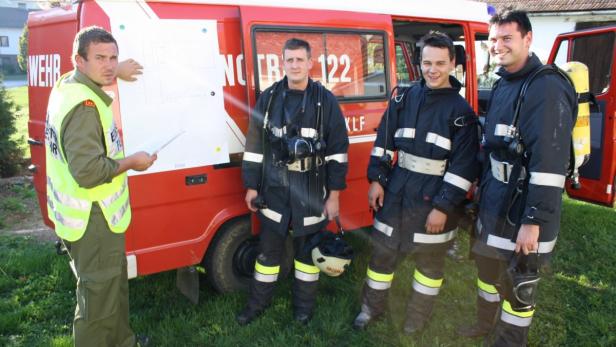 Eine Gruppe von Feuerwehrleuten steht vor einem roten Einsatzfahrzeug.