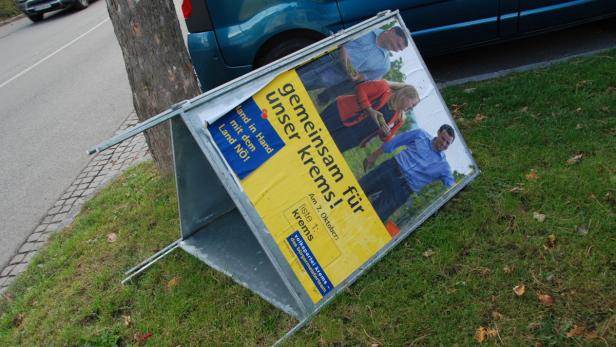 Ein umgefallenes Wahlplakat der Volkspartei Krems liegt auf einer Wiese.