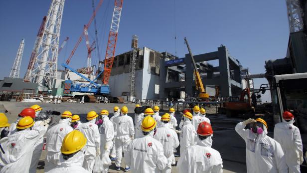 epa03631011 (FILE) A file picture dated 06 March 2013 shows members of the media wearing protective suits and masks escorted by TEPCO employees as they go on a visit near the No.4 reactor (C) and its foundation construction (R) for the storage of melted fuel rods at Tokyo Electric Power Co. (TEPCO)&#039;s tsunami-crippled Fukushima Daiichi nuclear power plant in Fukushima prefecture, Japan. According to Tokyo Electric Power Co (TEPCO) on 19 March 2013, systems for cooling spent fuel at a stricken Fukushima Daiichi Nuclear Power Plant were interrupted by a power cut. The Japanese nuclear power plant lost power before 7 pm local time on 18 March, affecting nine facilities including the spent fuel storage at reactors 1, 3 and 4. The problem did not interrupt the water injection being used to cool the actual reactors 1, 2 and 3, which suffered severe damage and meltdowns in the wake of the March 2011 earthquake and tsunami. TEPCO announced later in the day that the cooling system has been restored at the spent fuel storage pool of the reactor 1. EPA/ISSEI KATO / POOL