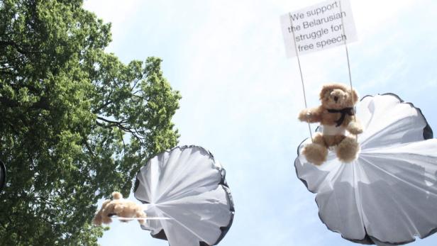 Teddybären schweben an Fallschirmen mit einem Schild, das die belarussische Bewegung für freie Meinungsäußerung unterstützt.