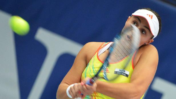 Eine Tennisspielerin schlägt einen Tennisball mit ihrem Schläger.