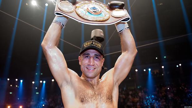 Ein Boxer mit einer „Camp David“-Kappe hält seinen Weltmeistergürtel hoch.