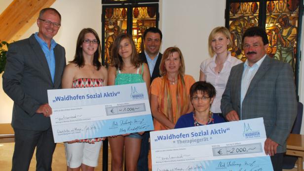 Eine Gruppe von Personen präsentiert Schecks der „Waidhofen Sozial Aktiv“ über 1.000 und 2.000 Euro.