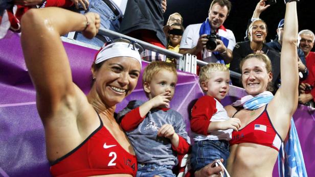 Die US-amerikanischen Beachvolleyballspielerinnen mit ihren Kindern feiern einen Sieg.