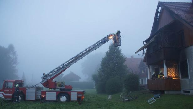 Feuerwehrleute bekämpfen einen Brand in einem Wohnhaus mit einer Drehleiter.