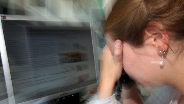 Eine Frau sitzt vor einem Computer und stützt ihren Kopf in die Hand.