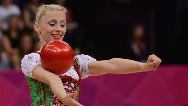Eine rhythmische Sportgymnastin mit einem roten Ball während einer Aufführung.