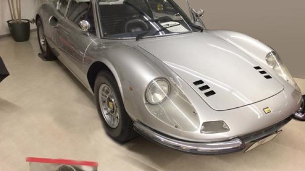 Ein silberfarbener Ferrari Dino 246 GT steht in einem Ausstellungsraum.