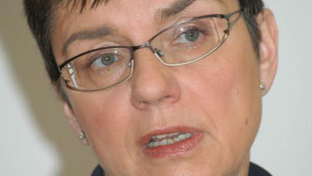 Eine Frau mit Brille und kurzem, dunklem Haar schaut in die Kamera.