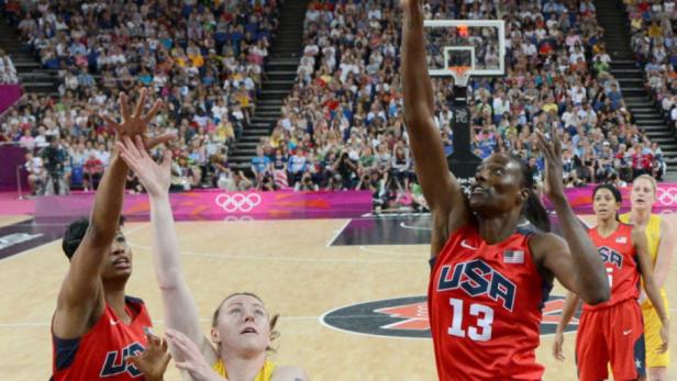 Eine US-amerikanische Basketballspielerin beim Wurf auf den Korb, umringt von Gegenspielerinnen und Zuschauern.