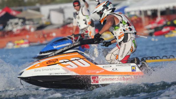 Ein Jetski-Fahrer rast auf einem orangefarbenen Jetski über das Wasser.
