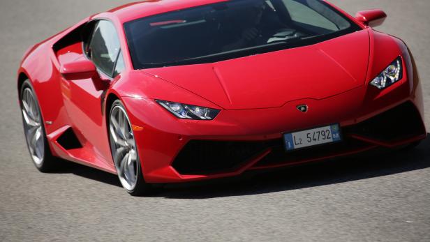 Ein roter Lamborghini Huracán fährt auf einer asphaltierten Straße.