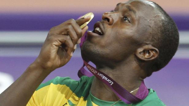 Usain Bolt beißt in seine Goldmedaille bei den Olympischen Spielen 2012 in London.