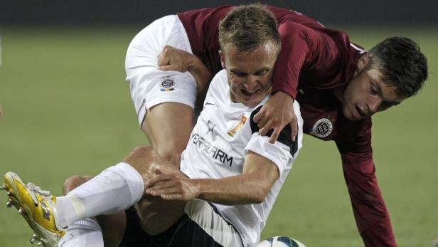 Zwei Fußballspieler kämpfen um den Ball während eines Spiels.