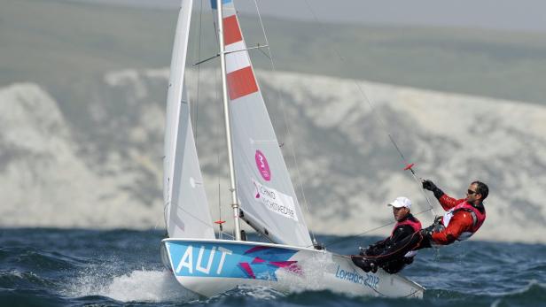 Ein Segelboot mit zwei Seglern bei einer Regatta vor der Küste.