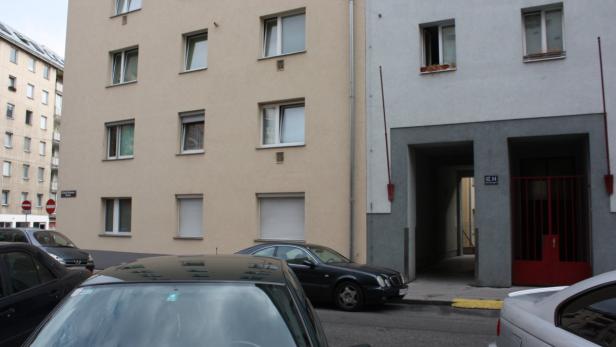 Mehrere Autos stehen vor einem Wohnhaus in einer Stadt.