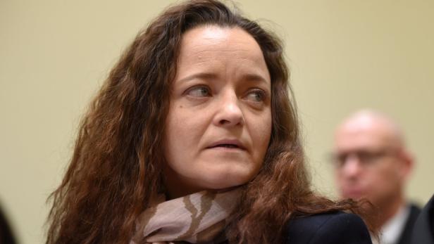 Eine Frau mit braunem, gewelltem Haar und einem Schal blickt nach rechts.