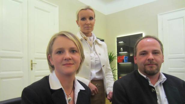 Drei Personen posieren in einem Büro für ein Foto.