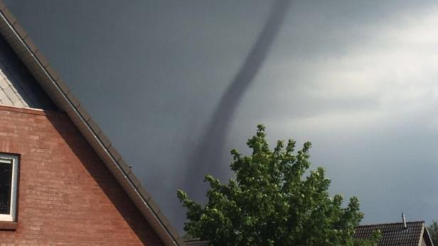 Ein Tornado ist in der Ferne über einem Wohngebiet zu sehen.