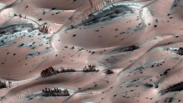 Dünenlandschaft mit dunklen Ablagerungen auf einem fernen Planeten, möglicherweise dem Mars.