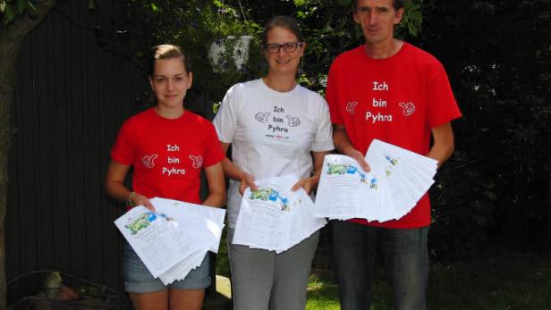 Drei Personen mit T-Shirts mit der Aufschrift „Ich bin Pyhra“ halten Flyer in der Hand.
