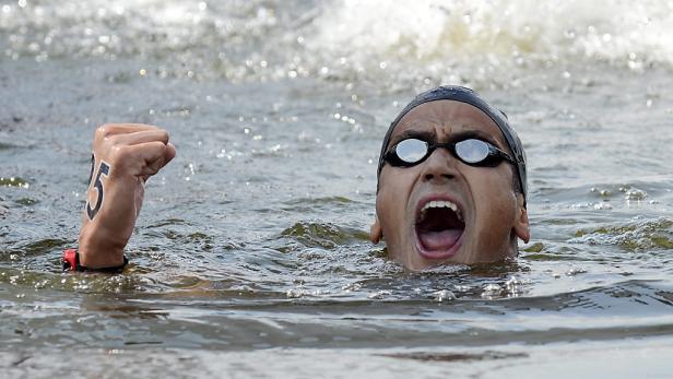 Ein Schwimmer mit der Nummer 15 auf der Hand jubelt im Wasser.