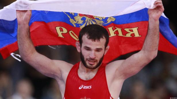 Ein Ringer hält eine russische Flagge hoch.