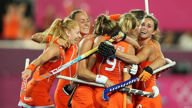 Niederländische Hockeyspielerinnen feiern gemeinsam in ihren orangefarbenen Trikots.