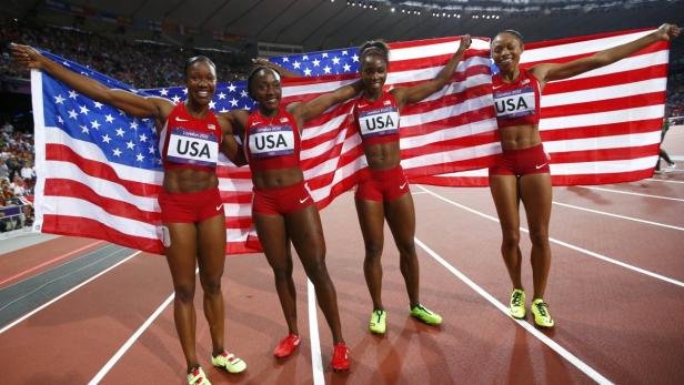 Das US-amerikanische 4x100-Meter-Staffelteam feiert mit der US-Flagge ihren Sieg.