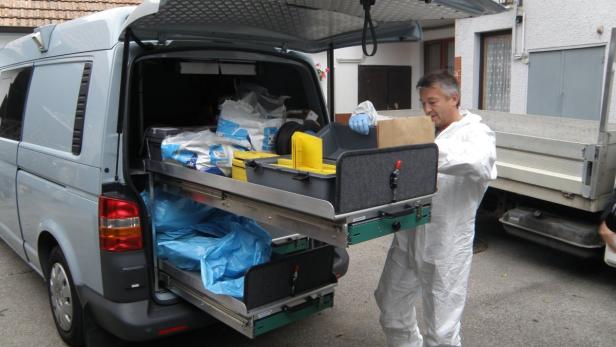 Ein Mann in Schutzanzug hantiert an einem Lieferwagen mit ausziehbaren Schubladen voller Ausrüstung.