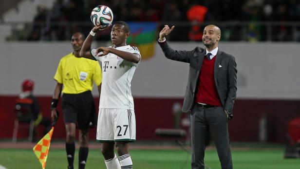 David Alaba mit einem Ball und Trainer Pep Guardiola am Spielfeldrand.
