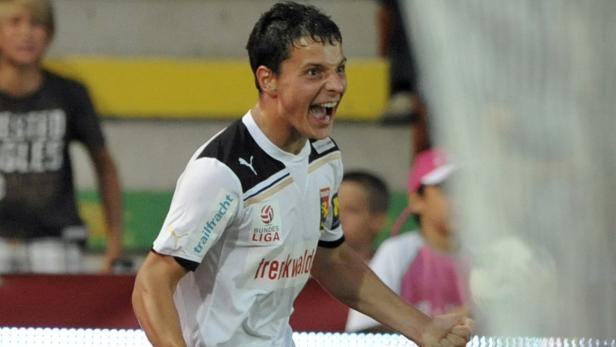 Ein jubelnder Fußballspieler im weißen Trikot der Bundesliga.