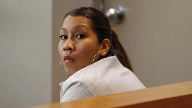 Eine Frau mit Ohrringen blickt über ihre Schulter.