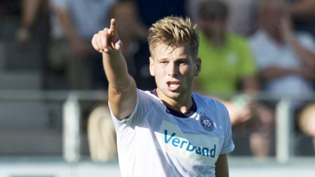 Ein Fußballspieler in einem weißen Trikot zeigt mit dem Finger nach oben.