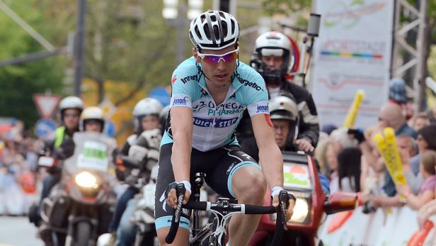 Ein Radrennfahrer fährt ein Rennen auf einer asphaltierten Straße.