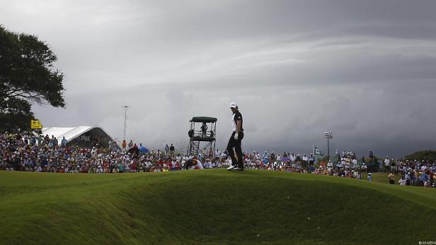 Ein Golfer steht vor einer Zuschauermenge auf einem Golfplatz.