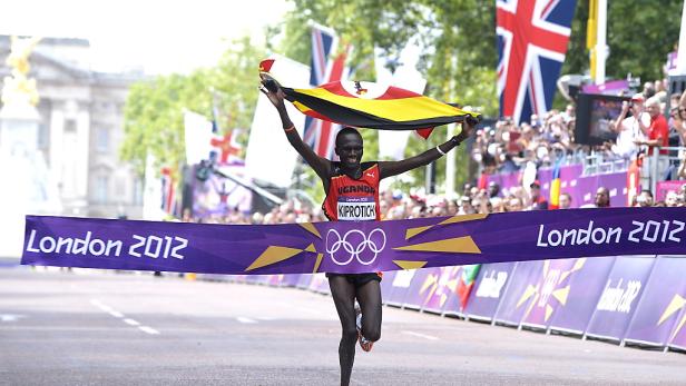 Stephen Kiprotich überquert die Ziellinie bei den Olympischen Spielen 2012 in London mit der ugandischen Flagge.