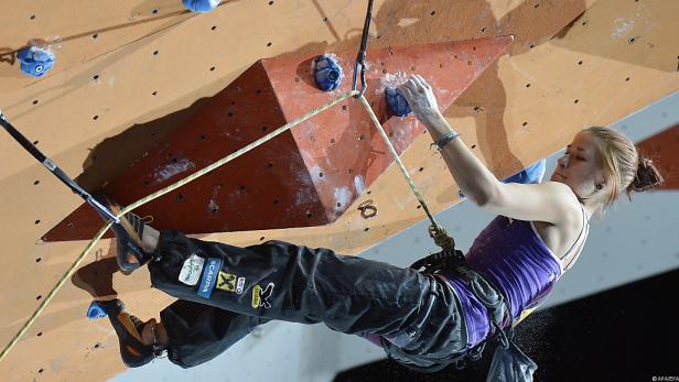 Eine Frau klettert an einer Kletterwand mit verschiedenen Griffen.