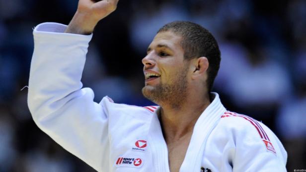 Ein Judoka im weißen Gi mit erhobenem Arm.