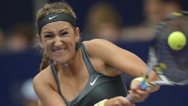 Eine Tennisspielerin schlägt mit einem Lächeln auf dem Gesicht einen Ball.