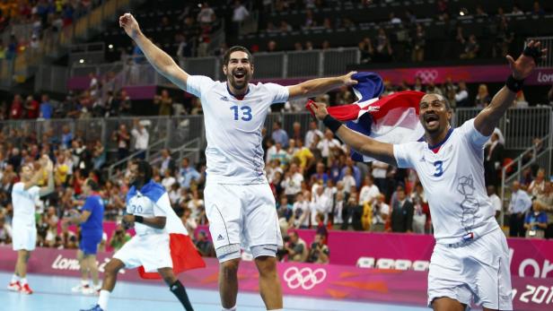 Französische Handballspieler feiern mit der Trikolore einen Sieg.