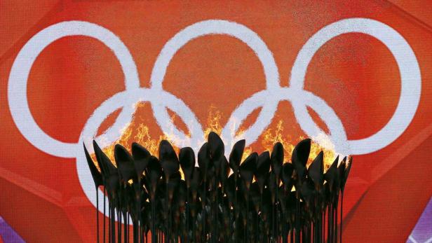 Die olympische Flamme brennt vor dem Hintergrund der olympischen Ringe.