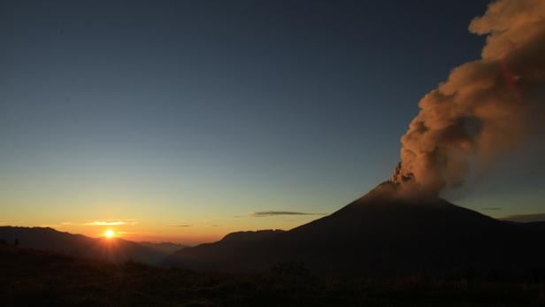 Bei Sonnenaufgang stößt ein Vulkan Rauch aus.