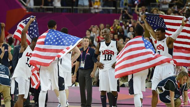 Das US-amerikanische Basketballteam feiert mit US-Flaggen einen Sieg.
