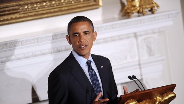 Barack Obama spricht an einem Rednerpult mit amerikanischer Flagge.