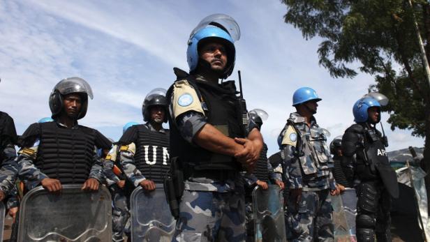 Eine Reihe von UN-Friedenssoldaten in blauer Camouflage-Uniform und Helmen stehen in einer Reihe.